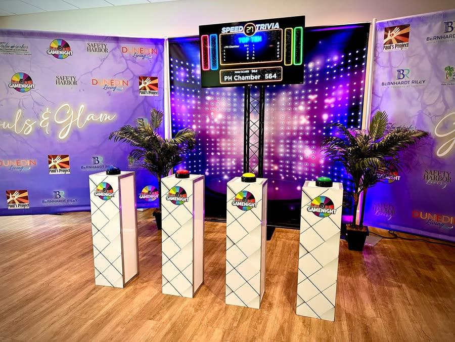 Four podiums with buzzers set up facing a Speed Trivia scoreboard in a function room